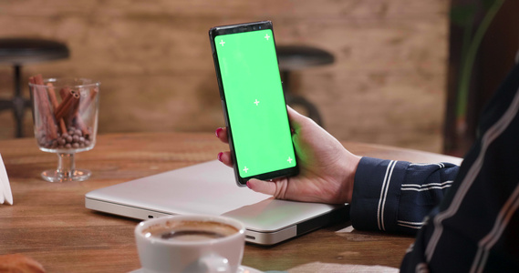 从右向左拍摄的幻灯片握着绿色屏幕智能手机的女性手掌视频