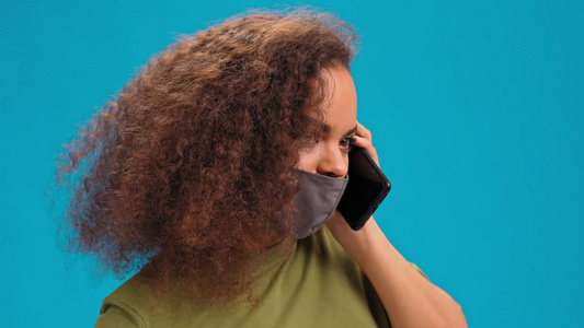 打电话时戴着可重复使用的棉灰色面罩将其固定在橄榄色视频