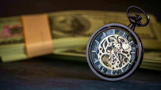 在黑暗背景中堆积着美元钞票时间短于时空的口袋手表和视频