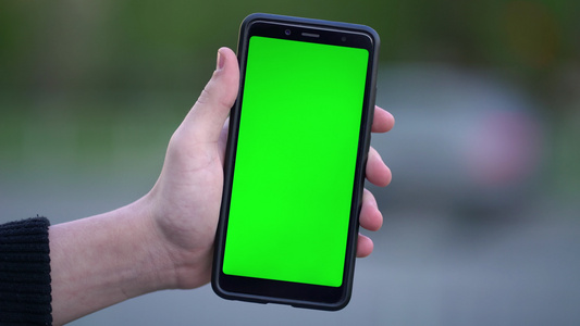男子在街上拿着假智能手机和绿色屏幕露天视频