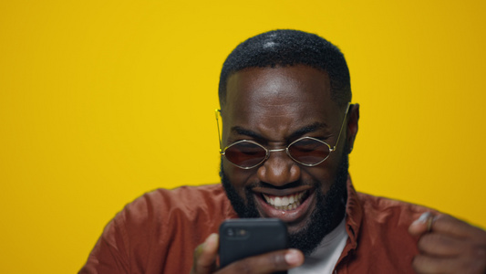 在演播室的智能手机上读到好消息的非洲男人肖像视频