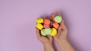 女性双手握着彩色饼干在紫色背景9秒视频