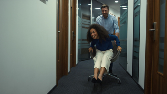 公司团队在走廊公司工作场所享受赛车办公椅的乐趣视频