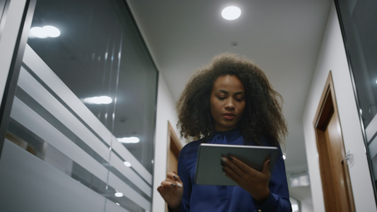 非裔美国女商务人士在办公室行走搜索公司的数字平板电脑视频