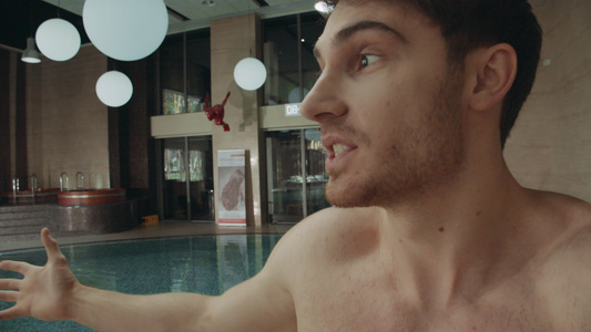 英俊的男人正对着镜头介绍泳池视频