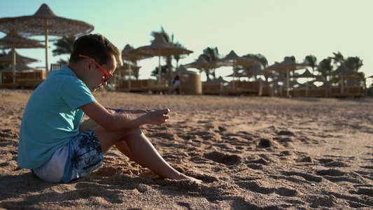 小男孩在海边玩手机游戏视频