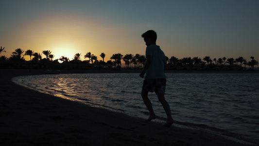 小男孩在日落时海上奔跑视频
