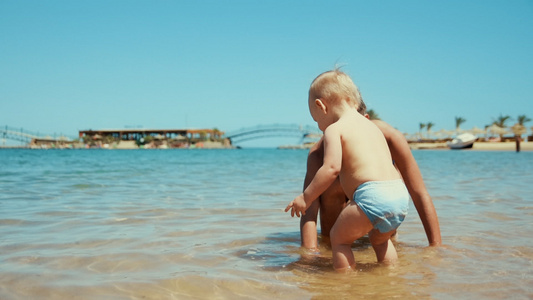小女孩在阳光明媚的海边和弟弟玩水视频