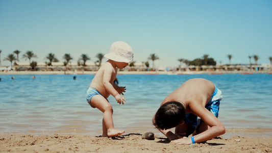 可爱的男孩和宝宝夏天暑假在海边玩耍视频