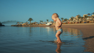 可爱的宝宝在温暖的海边沙滩上泼水24秒视频