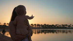 年轻母婴和可爱宝宝在度假胜地海滩享受美丽的夕阳12秒视频