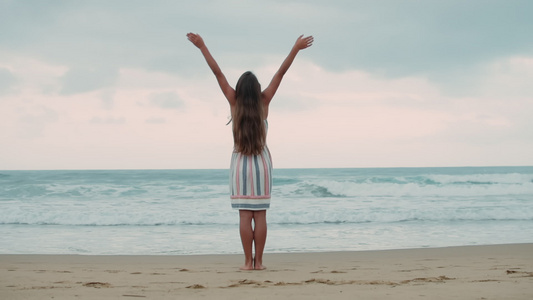 在海边举起手臂的年轻小女孩视频