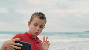 小男孩在海滩上拿着手机拍照14秒视频