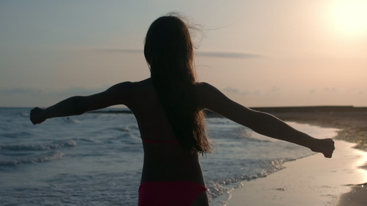 在沙滩上漂亮女孩逆光锻炼背影视频