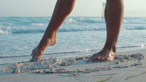 女孩用脚在沙滩上画画腿部特写20秒视频