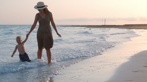 母亲在海滩牵着婴儿的手散步享受日落22秒视频