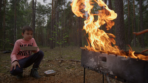 小男孩在树林烧烤篝火野营吃晚餐25秒视频