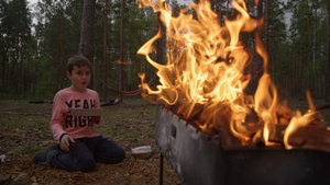 烧烤架上明亮的火焰照亮了坐在火炉旁的男孩的侧影11秒视频