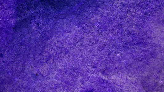 厚重的紫花岗岩岩石砖洞穴表面4k雨滴供室内壁纸用视频