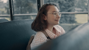 微笑的女学生戴着眼镜坐在公交车窗前14秒视频