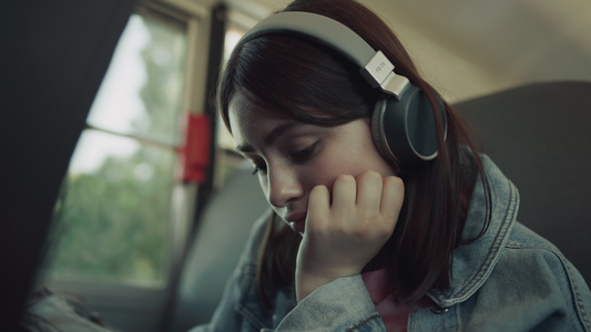 特写让女孩独自坐在校车上戴着耳机等待乘车视频