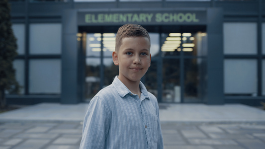 微笑的小学年龄男孩站在学校门口视频