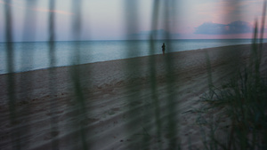 剪影女人在寒冷的早晨日出黄昏漫步沙滩12秒视频