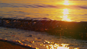 特写海浪在金色的早晨日出时溅起沙滩沙子19秒视频