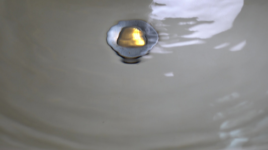 关闭水龙头和洗手盆在马桶里水滴缓缓落在水面上水面反射视频