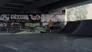 年轻的溜冰者在滑板公园的滑板上骑着涂鸦墙背景28秒视频