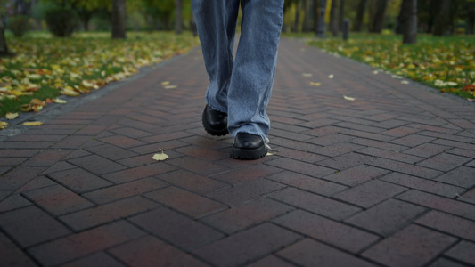 穿着靴子和牛仔裤的女性在秋天公园中行走视频