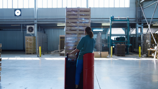 运输托盘的女仓库工人驾驶存储机移动箱子视频