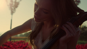 特写镜头激发了年轻女子在户外盛开的夏季花园里拉大提琴的灵感16秒视频