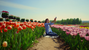 明亮的郁金香田和在花卉背景中自拍的年轻女性12秒视频