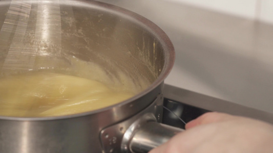 一个专业厨师在碗里加热奶油的近镜头视频