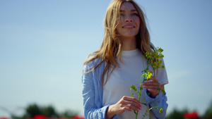 幸福的女人长着美丽的长发在蓝天背景下拿着野生植物15秒视频