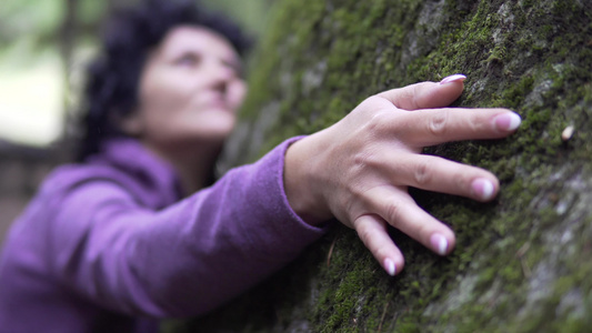 恋爱中的幸福女人放松地拥抱着一块巨大的石头在森林里视频