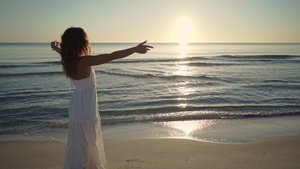 年轻可爱的白种金发女子身着白色长裙望着海边日落或黎明21秒视频