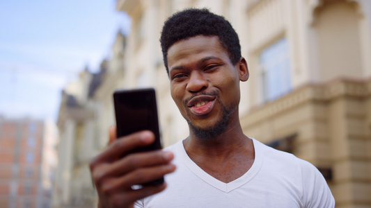 兴奋的非洲家伙在街上有视频电话 男人在户外做手势视频