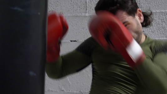 拳击手套的拳击手在搏击俱乐部的战斗训练中踢战斗袋拳击手视频