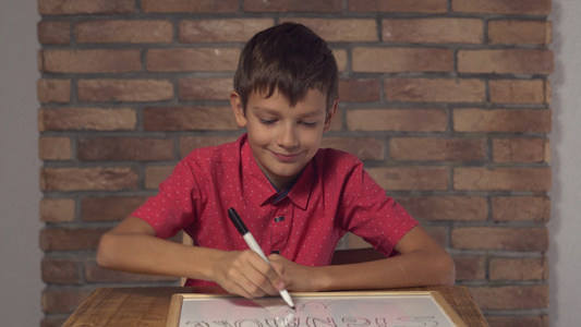 坐在桌子上的孩子拿着翻页图背面的红砖墙上有字母签名视频