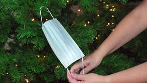 圣诞节用口罩作为装饰挂在绿树上灯光照亮19秒视频