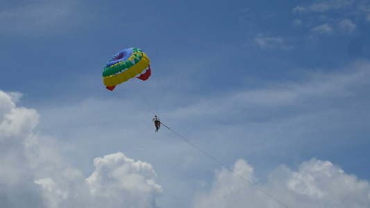 滑翔伞活动多彩的滑翔伞翼与游客在蓝天多云极限运动海滩视频