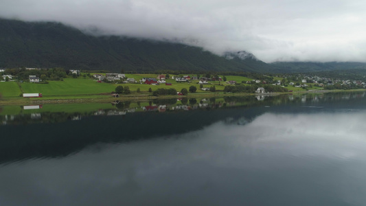 小小镇和湖面反射云雾多的夏季日诺威绿色风景空中观察视频