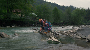 男人和女坐在河边的岩石上 一起在空气中泼水18秒视频