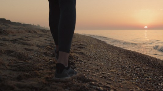 特写苗条的女人脚在日落时分走在沙滩上视频