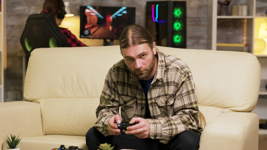 坐在沙发上玩电子游戏的有重点的胡须男子视频