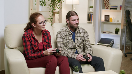 丈夫和妻子坐在沙发上玩电子游戏视频