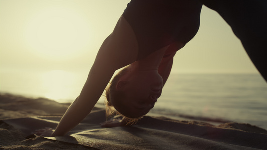 瑜珈女孩练习体式站立姿势在沙滩上的脸狗视频