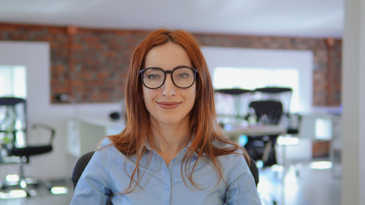 红头发女性在工作场所微笑的肖像视频